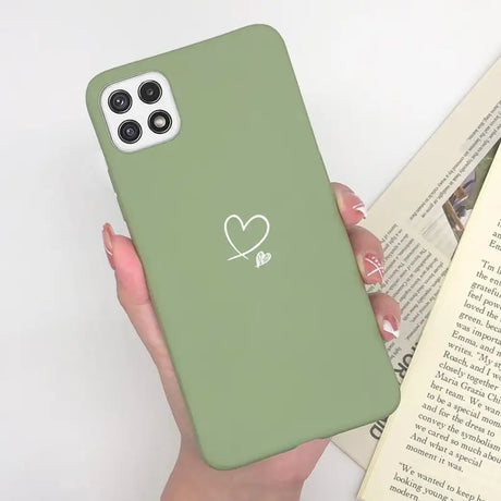 a woman holding a green phone case with a heart on it