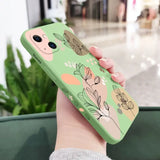 a woman holding a green phone case with flowers on it