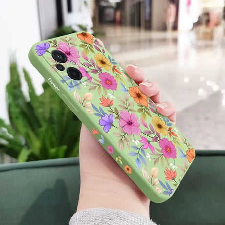 a woman holding a green phone case with flowers on it