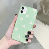 a woman holding a green phone case with daisies on it