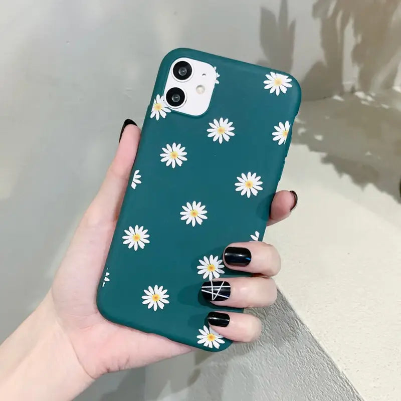 a woman holding a green phone case with white daisies on it