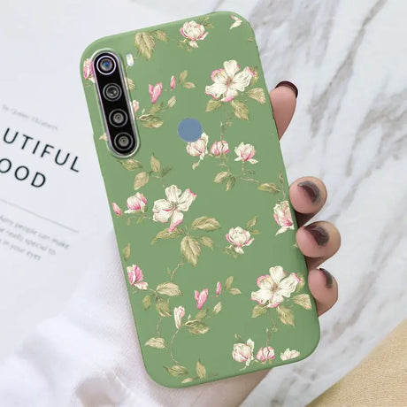 a woman holding a green phone case with pink flowers on it