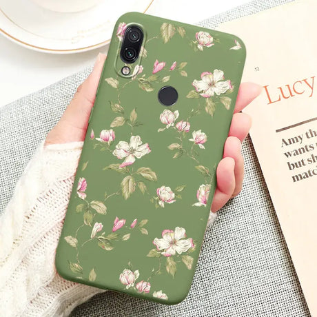 a woman holding a green phone case with pink flowers on it