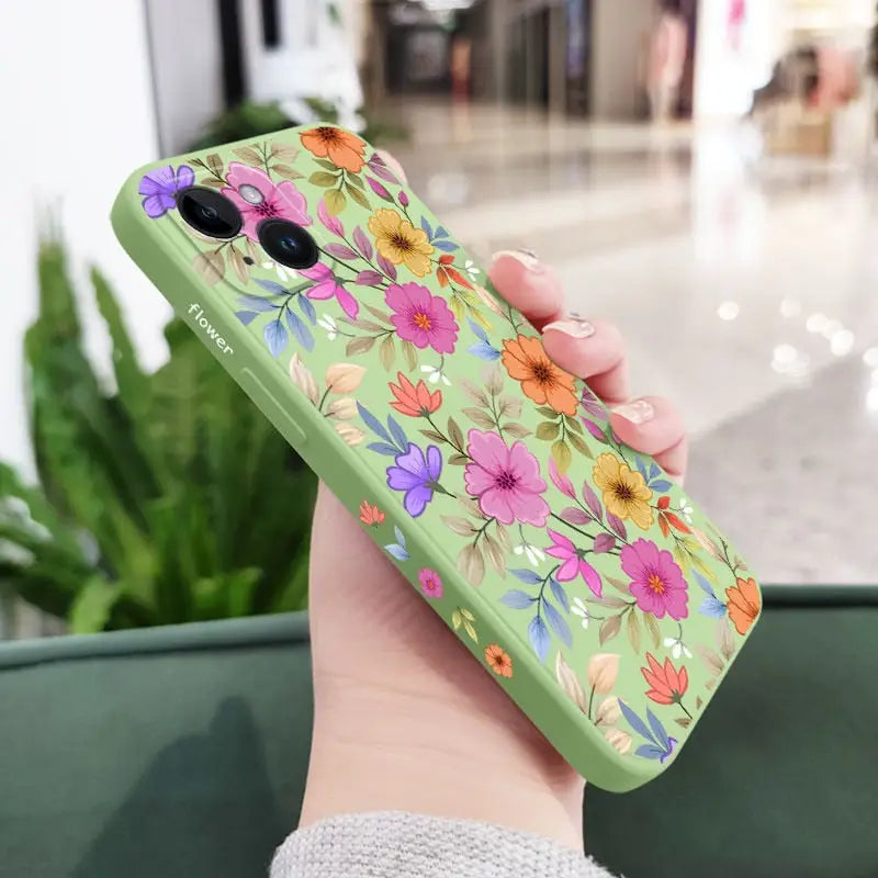 a woman holding a green phone case with flowers on it