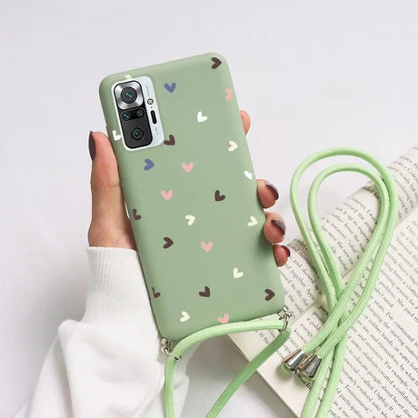 a woman holding a green phone case with hearts on it