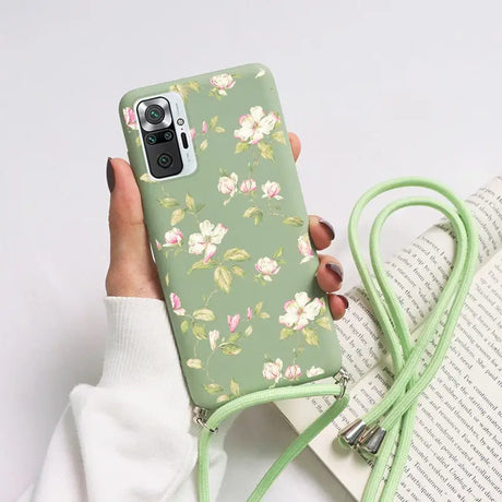 a woman holding a green phone case with flowers on it