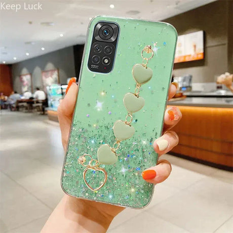 a woman holding a green phone case with heart charms