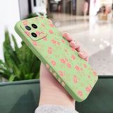 a woman holding a green phone case with pink flowers on it