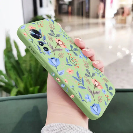 a woman holding a green phone case with a floral pattern