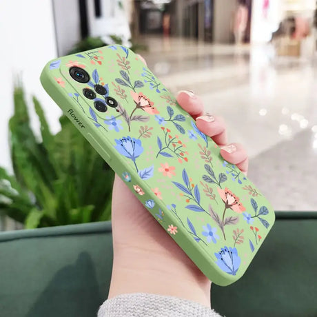 a woman holding a green phone case with flowers on it