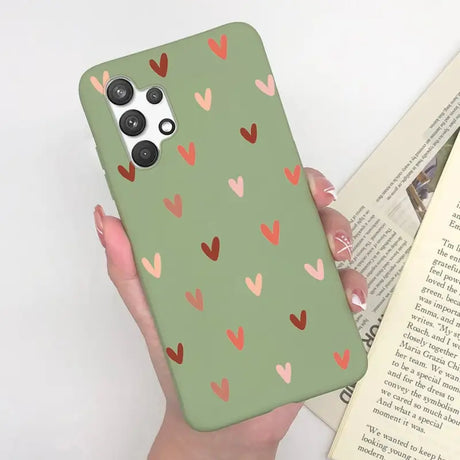 a woman holding a green phone case with hearts on it