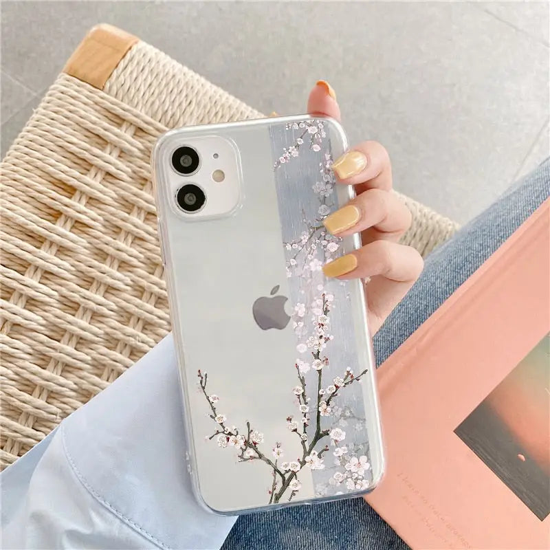a woman holding a phone case with a cherry blossom on it