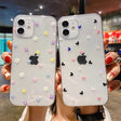 a woman holding up two iphone cases with hearts and flowers