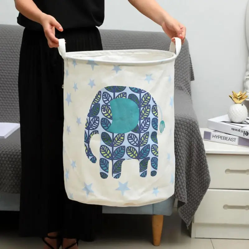 a woman holding a large laundry bag with a blue elephant design