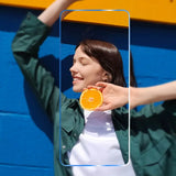 a woman holding an orange in front of her face