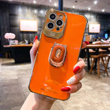 a woman holding an orange phone case with a ring on it