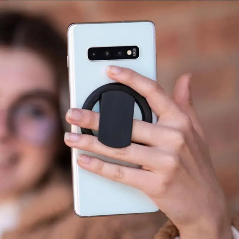 a woman holding a phone with a black ring on it