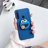 a woman holding a phone case with a blue monster face