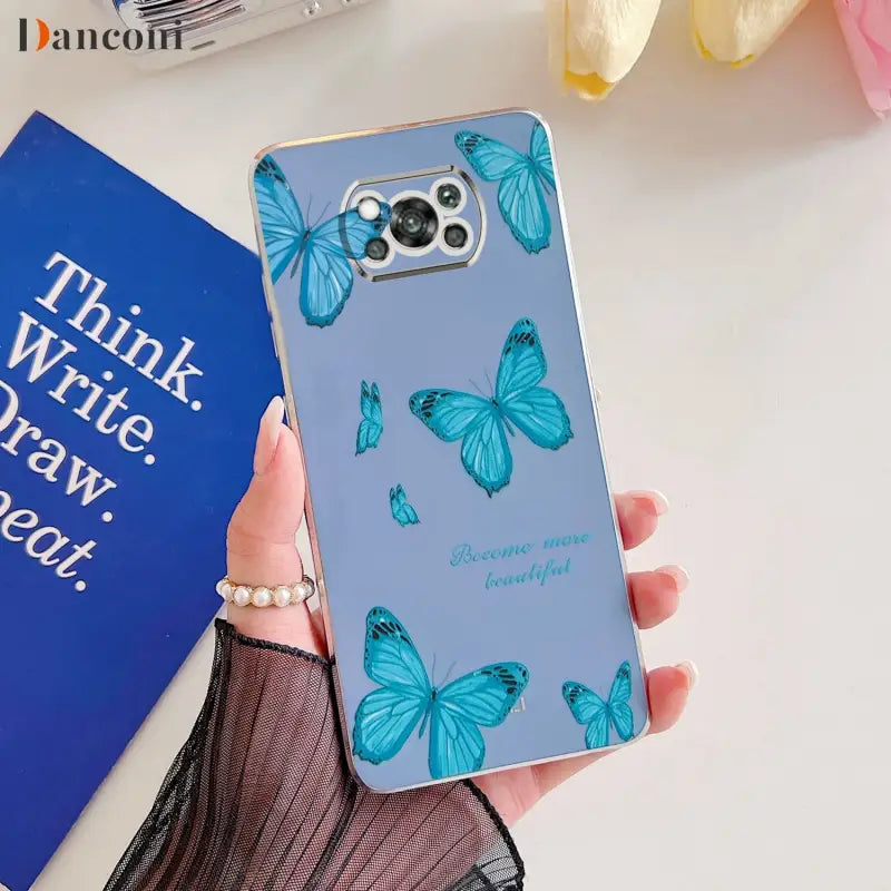 a woman holding a phone case with blue butterflies on it