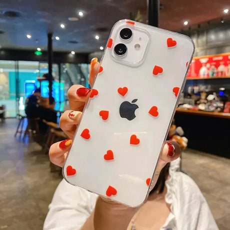 a woman holding up a phone case with hearts on it