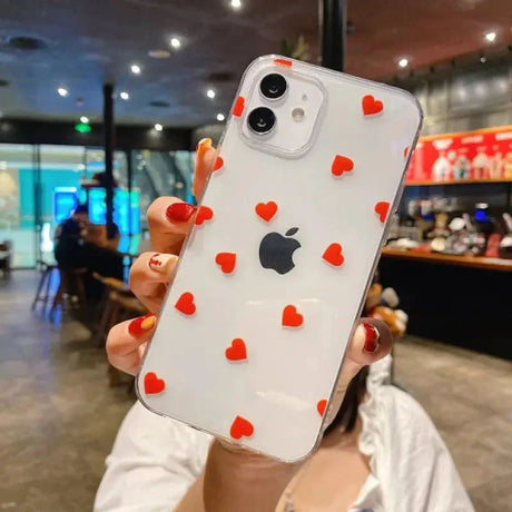 a woman holding up a phone case with hearts on it