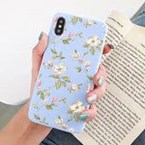 a woman holding a phone case with flowers on it