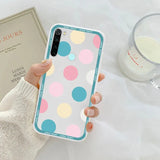 a woman holding a phone case with colorful circles on it