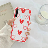 a woman holding a phone case with red hearts on it