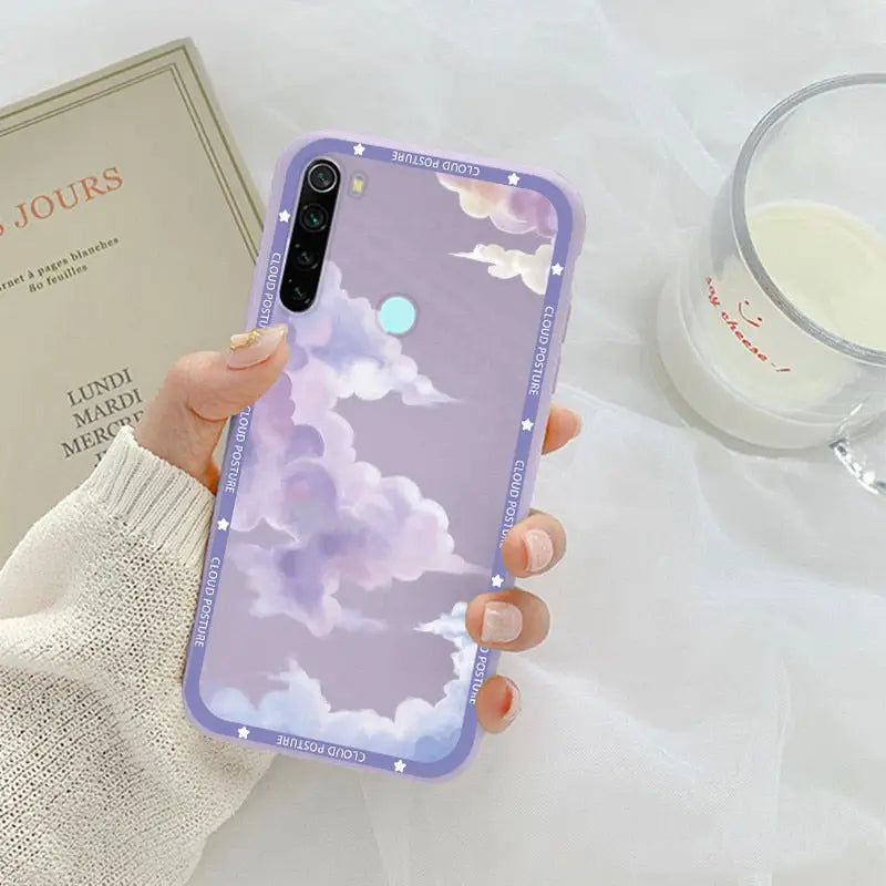 a woman holding a phone case with a purple sky and clouds pattern