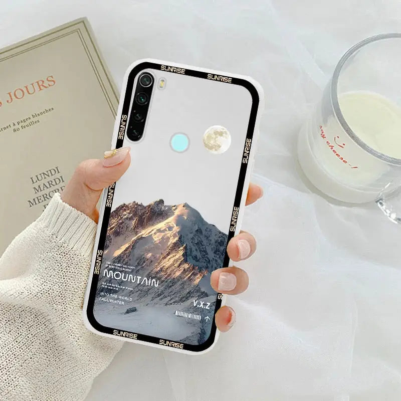 a woman holding a phone case with a mountain scene on it