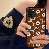 a woman holding a phone case with a brown flower pattern