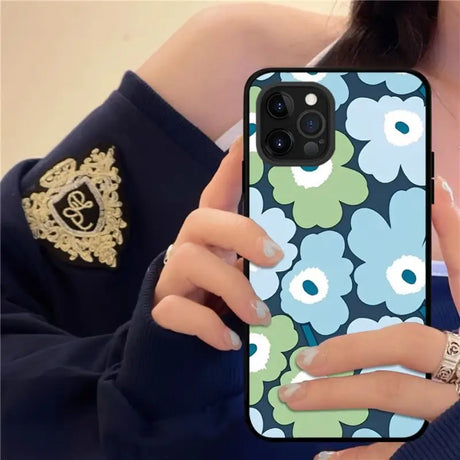 a woman holding a phone case with flowers on it