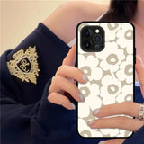 a woman holding a phone case with a white flower pattern