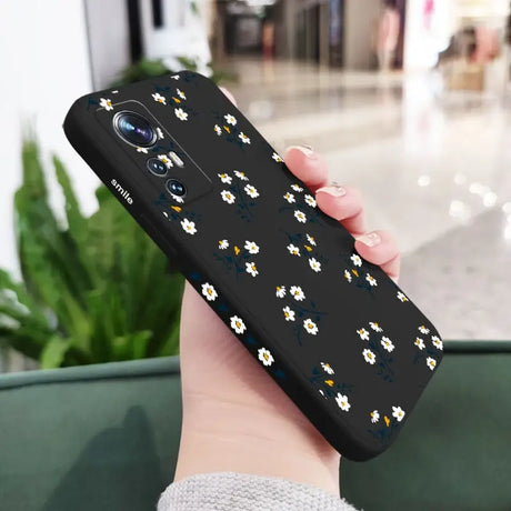 a woman holding a phone case with white flowers on it