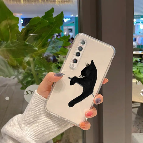 a woman holding up a phone case with a black cat on it