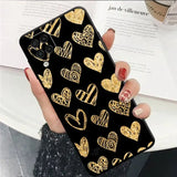 a woman holding a phone case with gold hearts on it