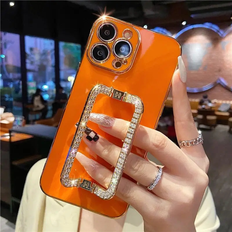 a woman holding a phone case with a diamond ring on it