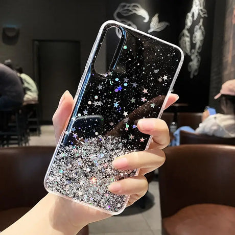 a woman holding up a phone case with glitter stars