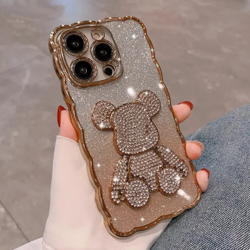a woman holding a gold iphone case with a teddy bear