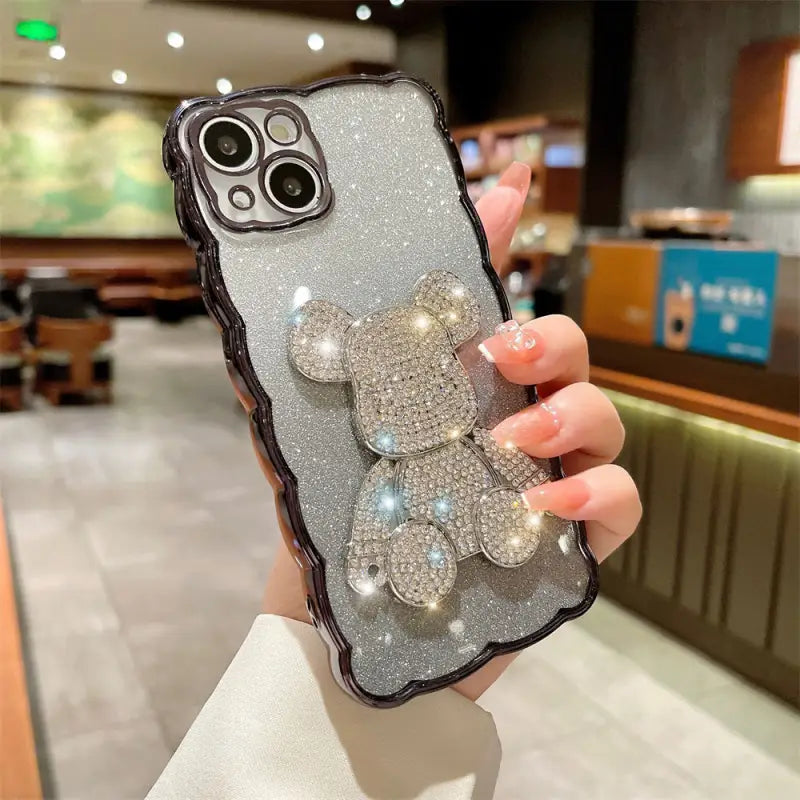a woman holding a phone case with a silver glitter bow