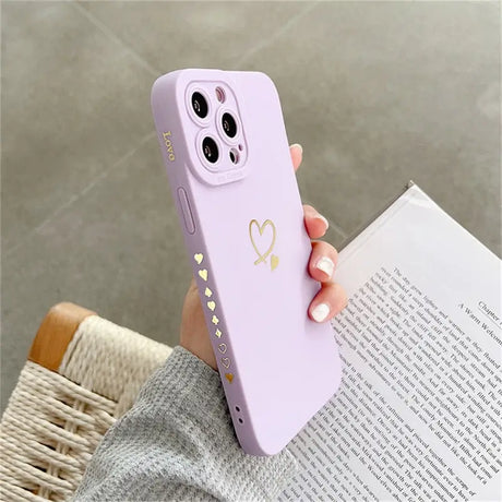 a woman holding a pink phone case with a heart on it