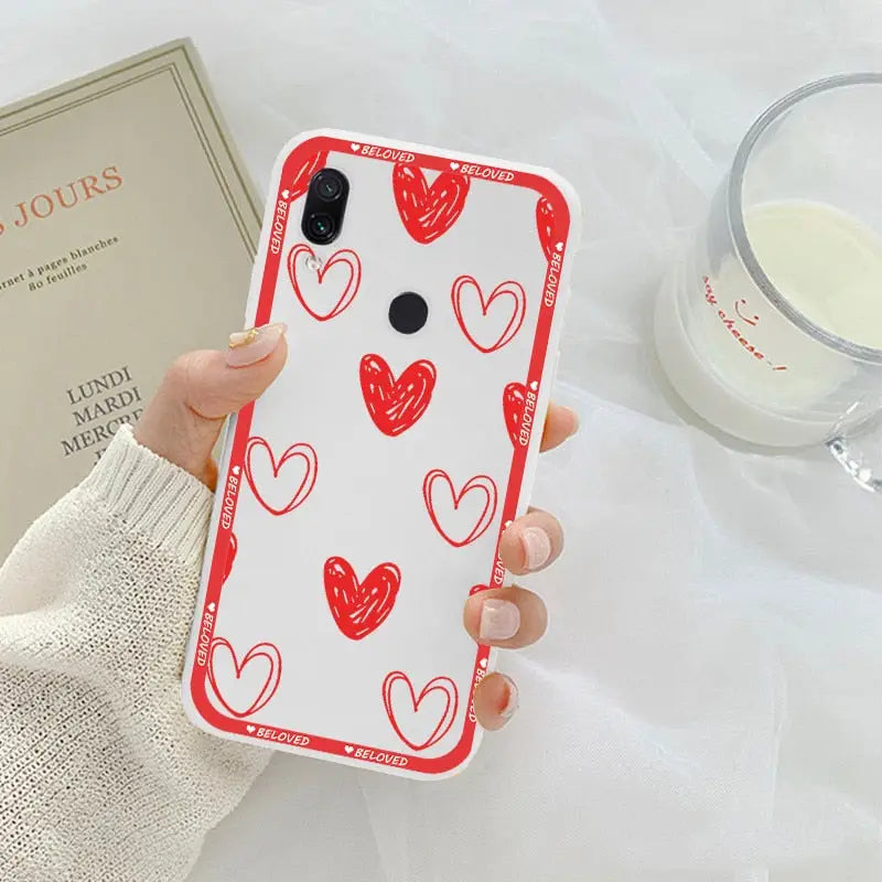 a woman holding a phone case with red hearts on it
