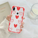 a woman holding a phone case with red hearts on it