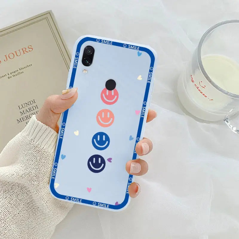 a woman holding a phone case with a smiley face on it