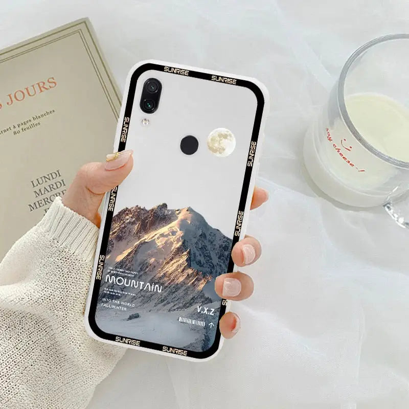 a woman holding a phone case with a mountain scene on it