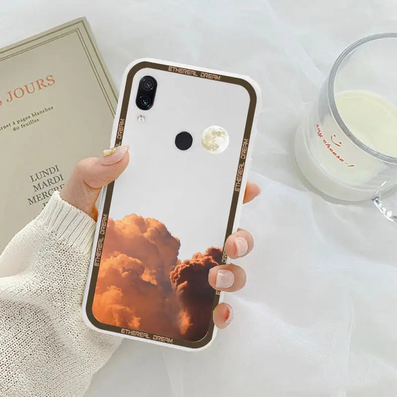 a woman holding a phone case with a photo of a cloud