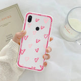 a woman holding a pink phone case with hearts on it