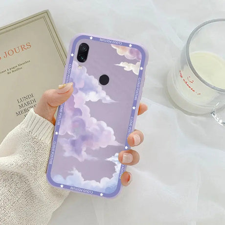 a woman holding a phone case with clouds on it