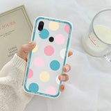 a woman holding a phone case with a colorful polka dot pattern