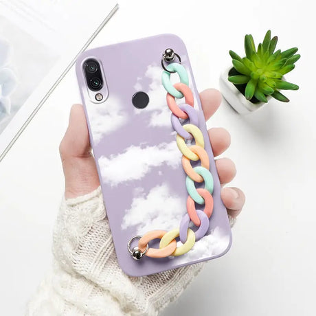 a woman holding a phone case with a cloud and rainbow colored rings